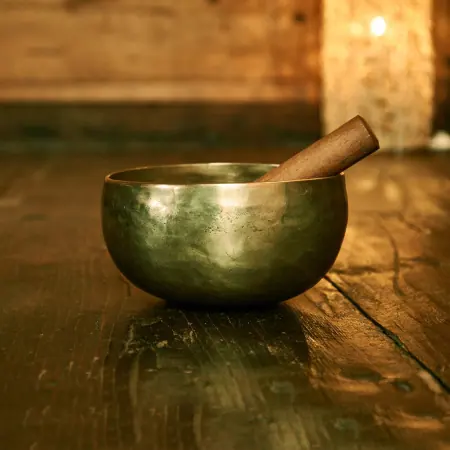 Klangschale aus Messing mit Klöppel auf einem Holzboden